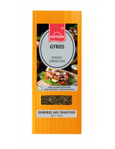Flachbeutel mit der Aufschrift „GYROS“, im Hintergrund Gyrosgericht mit Zwiebeln und frischen Kräutern.
