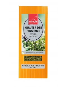 Flachbeutel mit der Aufschrift „KRÄUTER DER PROVENCE Gewürzmischung“, dahinter verschiedene frische Kräuter.