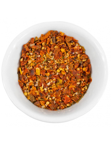 Weiße Schale, gefüllt mit grober Gewürz- und Gemüsemischung in Orange-, Rot- und Gelbtönen mit sichtbaren Kräuterstücken.