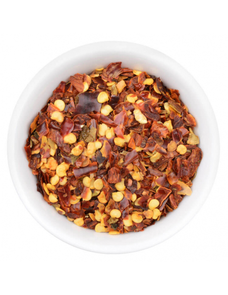 Weiße Schale gefüllt mit getrockneten Chili-Flocken in verschiedenen Rottönen. Scharfes, grobes Gewürz sichtbar. Weiße Schale gefüllt mit getrockneten Chili-Flocken in verschiedenen Rottönen. Scharfes, grobes Gewürz sichtbar.