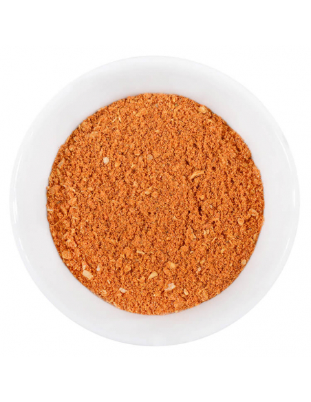 Orangene Gewürzmischung mit sichtbaren Kräuterstücken in weißer Schale von oben.