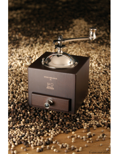 Die Mühle steht dekorativ auf einem Holzuntergrund in Szene gesetzt.