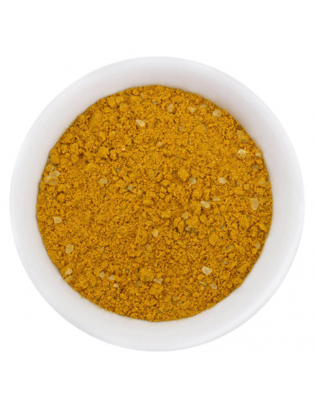Fein gemahlenes gelbes Madras Currypulver mit Gewürzstückchen in weißer Schale, von oben fotografiert