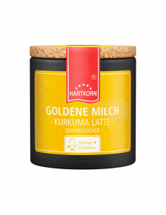 Pappdose mit Korkdeckel und gelbem Etikett, beschriftet mit „Goldene Milch – Kurkuma Latte“.