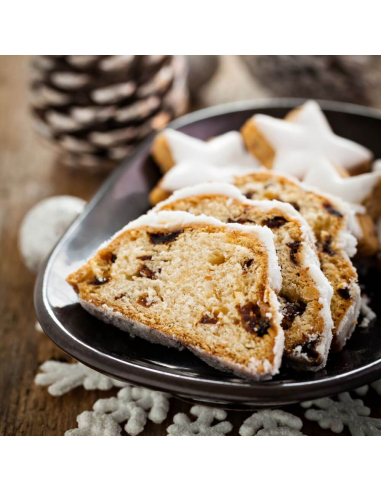 Drei Scheiben Christstollen mit Puderzucker auf dunklem Teller, dekoriert mit Weihnachtssternen.