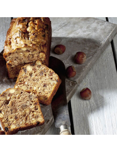 Aufgeschnittenes Früchtebrot auf rustikalem Holzbrett mit verstreuten Haselnüssen Aufgeschnittenes Früchtebrot auf rustikalem Holzbrett mit verstreuten Haselnüssen