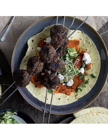 Dunkle Hackfleischspieße auf Fladenbrot mit Tomatensauce, Sprossen und Feta. Dunkle Hackfleischspieße auf Fladenbrot mit Tomatensauce, Sprossen und Feta.
