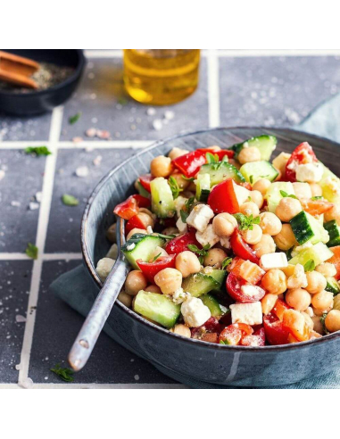 bunte salatschüssel mit kichererbsen, tomaten und feta auf gefliestem untergrund