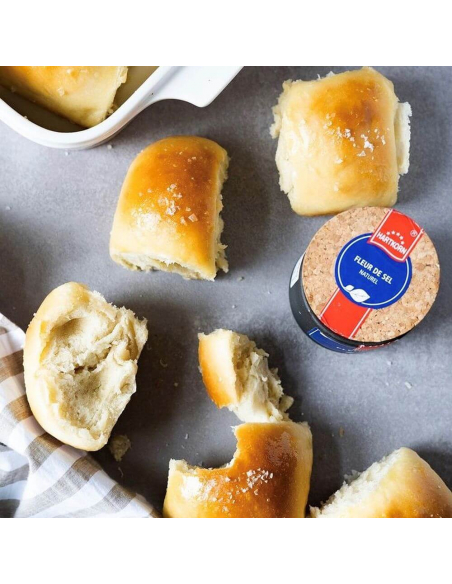 Weiche goldbraune Milchbrötchen, daneben die geöffnete Dose „FLEUR DE SEL“. Weiche goldbraune Milchbrötchen, daneben die geöffnete Dose „FLEUR DE SEL“.