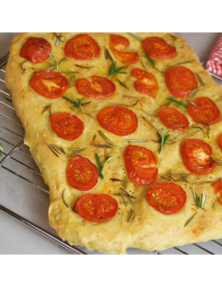 Ofenfrisches Focaccia mit Tomatenscheiben und Rosmarin auf einem Kuchengitter. Ofenfrisches Focaccia mit Tomatenscheiben und Rosmarin auf einem Kuchengitter.