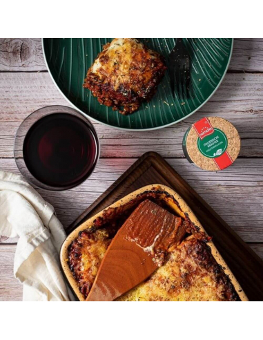 Auflaufform mit Lasagne, angerichtetes Stück auf grünem Teller, daneben Rotweinglas