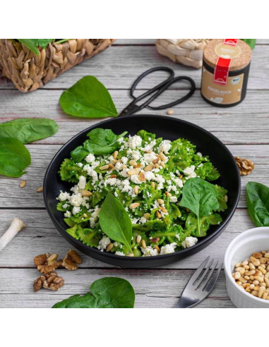 Schwarzer Teller mit Brokkolisalat, Feta, Spinatblättern und Pinienkernen