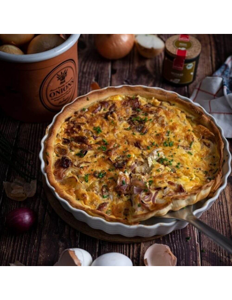 Runde Zwiebelquiche mit goldbrauner Kruste in Keramikform Runde Zwiebelquiche mit goldbrauner Kruste in Keramikform