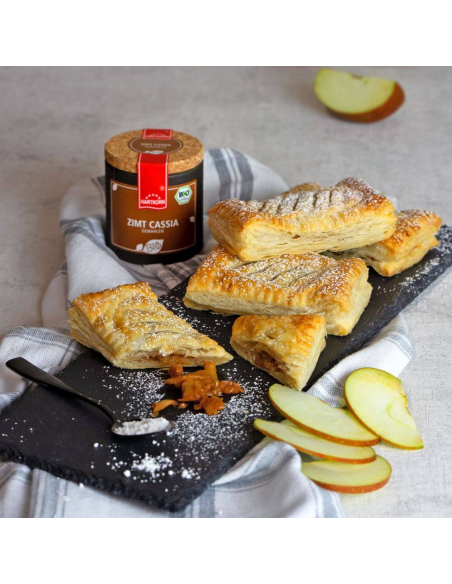 Blätterteigtaschen mit Apfelfüllung und Puderzucker auf Schieferplatte