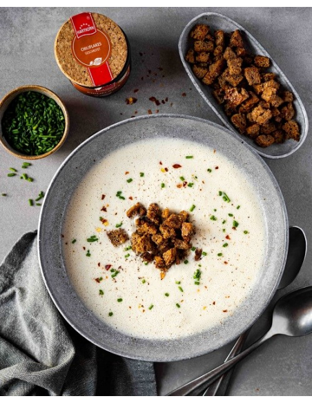 Teller mit heller Suppe, Croutons und roten Chiliflocken Teller mit heller Suppe, Croutons und roten Chiliflocken