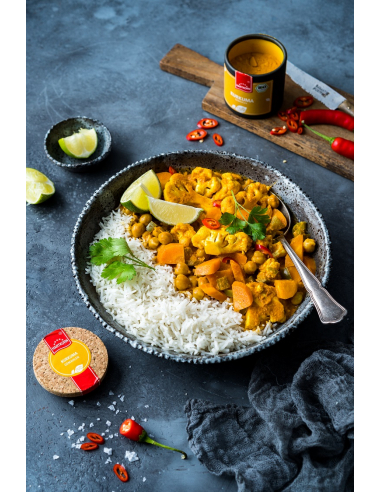 Schale mit Reis und Currygericht mit Gemüse, Limetten und Koriander