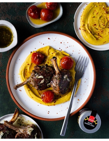 Bohnen Curry Dip – Lammkoteletts mit gelbem Curry-Hummus und Ofentomaten auf weißem Teller, daneben  Madras Currypulver