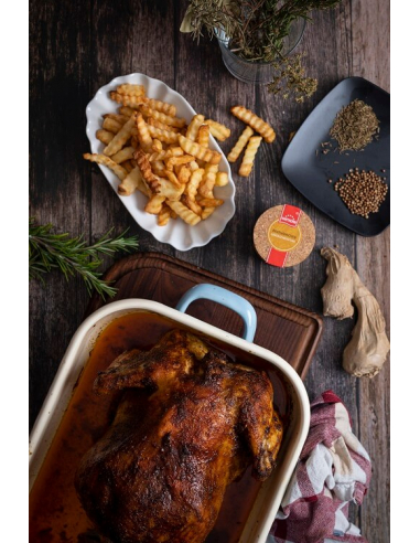 Gebratenes Hähnchen in Auflaufform mit Pommes, Gewürzen und Dose auf Holzuntergrund
