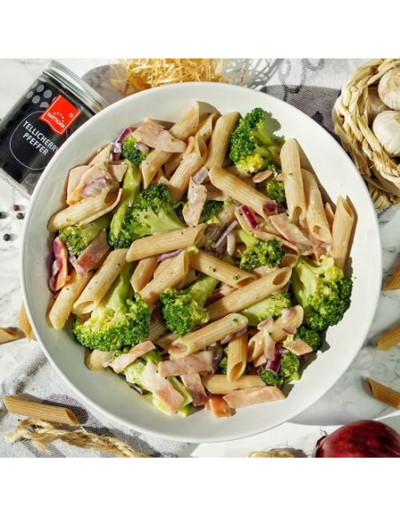 Pasta mit Brokkoli, Schinken und Sahnesoße auf Teller, daneben Hartkorn Tellicherry Pfeffer Pasta mit Brokkoli, Schinken und Sahnesoße auf Teller, daneben Hartkorn Tellicherry Pfeffer