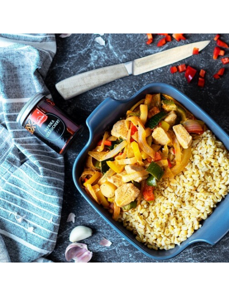 Paprika-Hähnchenpfanne mit Gemüse und Bulgur in blauer Form, daneben Glas mit Hartkorn-Logo und geräuchertem Paprikapulver Paprika-Hähnchenpfanne mit Gemüse und Bulgur in blauer Form, daneben Glas mit Hartkorn-Logo und geräuchertem Paprikapulver