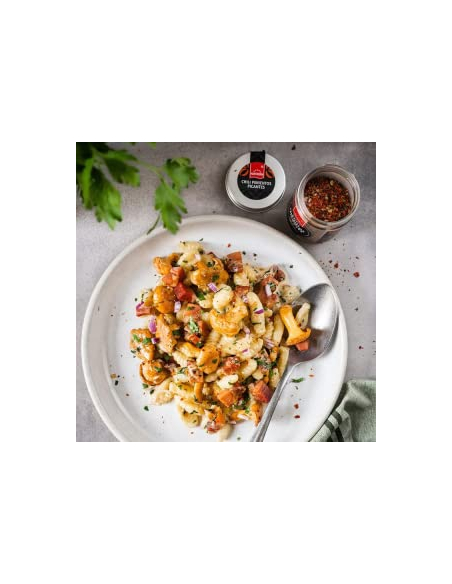 Pasta mit Speck, Zwiebeln und Chili-Gewürz auf weißem Teller, daneben Hartkorn Chili Pimientos Picantes