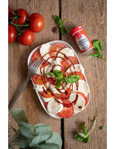 Caprese-Salat mit Tomaten, Mozzarella und Basilikumblättern auf einem weißen Teller, daneben die Produktdose.