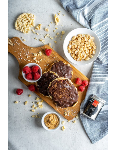 Schokoreiswaffeln mit Erdnüssen, Himbeeren und Erdnusscreme auf Holzbrett.
