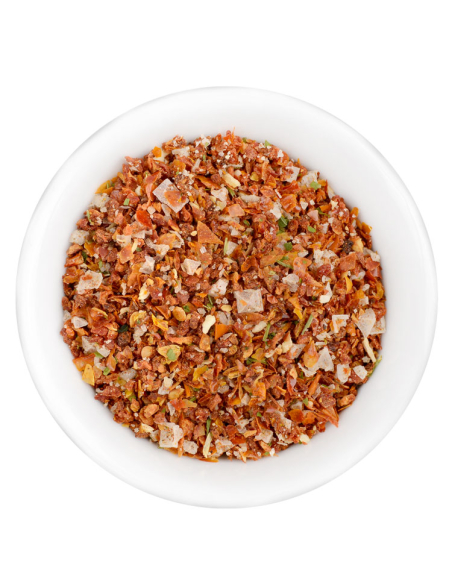 Eine weiße Schale gefüllt mit einer bunten, grobkörnigen Gewürz- und Kräutermischung in Rot-, Orange- und Grüntönen.