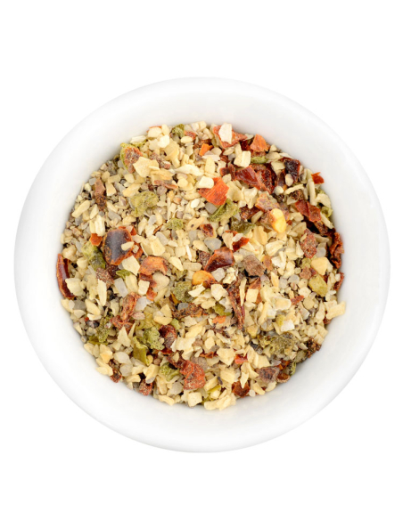 Eine weiße Schale gefüllt mit einer groben, bunten Gewürz-Gemüsemischung mit roten, grünen und beigen Bestandteilen.