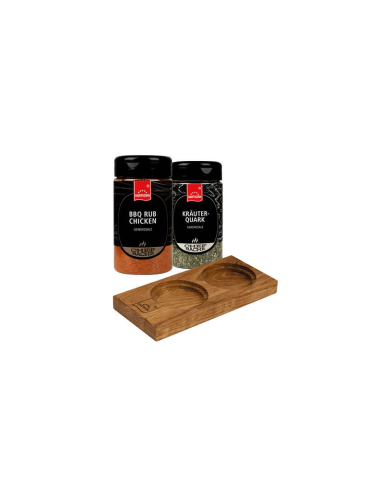 Zwei schwarze Gewürzdosen mit rotem Etikett stehen neben einem  Holzbrett mit zwei Aussparungen.