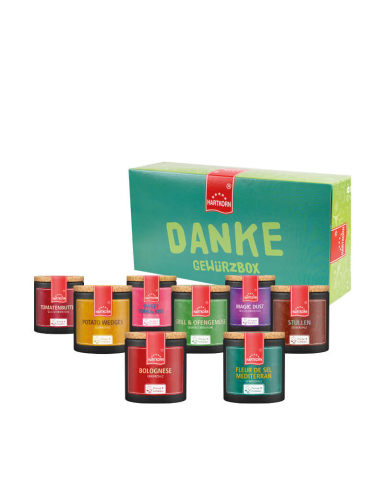 Geschenkbox mit der Aufschrift „Bestseller Gewürzbox“. Davor bunte Pappdosen mit Korkdeckel, die verschiedene Gewürze enthalten.