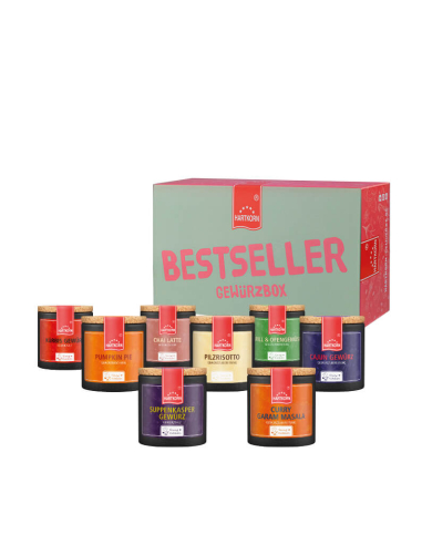 Geschenkbox mit der Aufschrift „Bestseller Gewürzbox“. Davor bunte Pappdosen mit Korkdeckel, die verschiedene Gewürze enthalten.