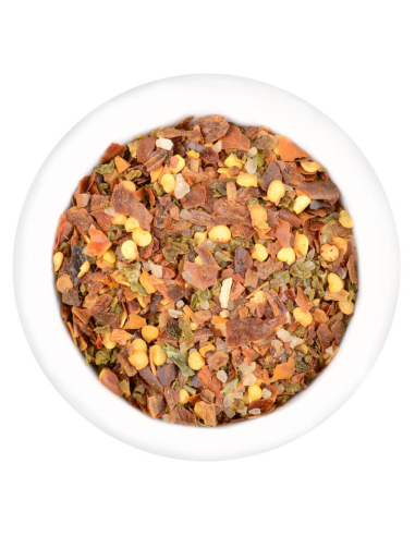 Scharfe Chiliflocken in Orange-, Rot- und Gelbtönen in weißer Schale.