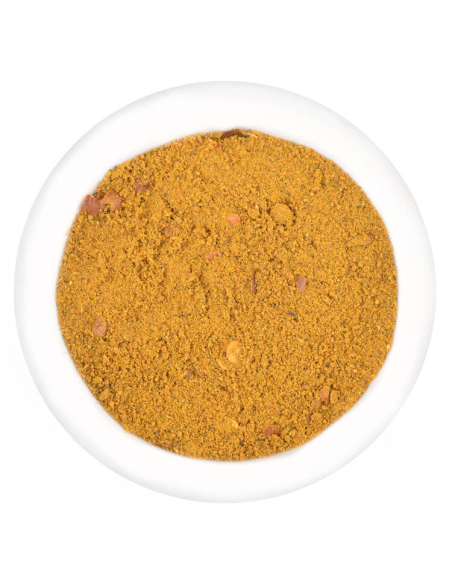 Bräunlich-gelbe Gewürzmischung mit feinen und groben Partikeln in weißer Schale. Bräunlich-gelbe Gewürzmischung mit feinen und groben Partikeln in weißer Schale.
