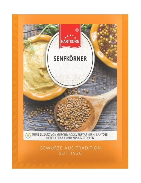 Flachbeutel mit Senfkörnern vor einer Schale Senf und Holzlöffel mit Körnern Flachbeutel mit Senfkörnern vor einer Schale Senf und Holzlöffel mit Körnern