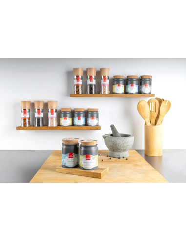 Regal mit Keramiktöpfchen und Gewürzmühlen darunter zwei schwarze Keramiktöpfchen mit Holzdeckel auf einem Holztablett.