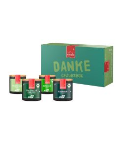Grüne Geschenkbox mit rotem Etikett, der Schriftzug „DANKE GEWÜRZE“, davor stehen vier Pappdosen in verschiedenen Farben.