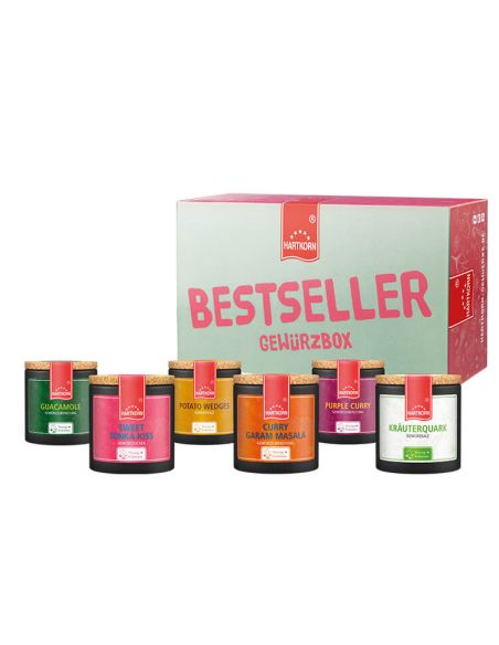 Mint-rosa Box mit der Aufschrift „Bestseller Gewürzbox“, davor sechs bunte Pappdosen mit Gewürzen.