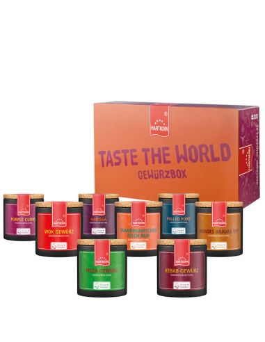 Box mit der Aufschrift „Taste the World Gewürzbox“, davor neun Keramiktöpfchen in kräftigen Farben.