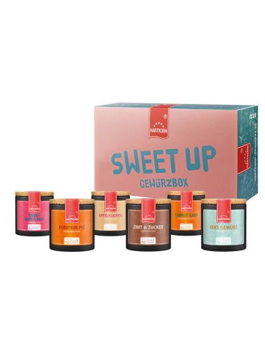 Box mit der Aufschrift „Sweet Up Gewürzbox“, davor sieben farbenfrohe Pappdosen mit unterschiedlichen Etiketten.