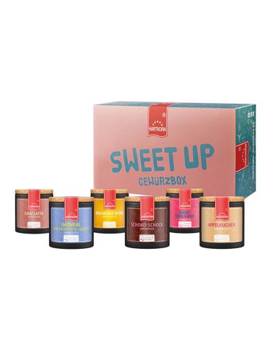 Box mit der Aufschrift „Sweet Up Gewürzbox“, davor sieben farbenfrohe Keramiktöpfchen mit unterschiedlichen Etiketten.
