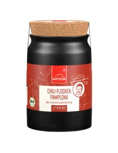 Schwarzes Keramiktöpfchen mit Korkdeckel. Rotes Etikett mit rotem Band: Chili Flocken Pamplona‘. BIO-Siegel sichtbar.