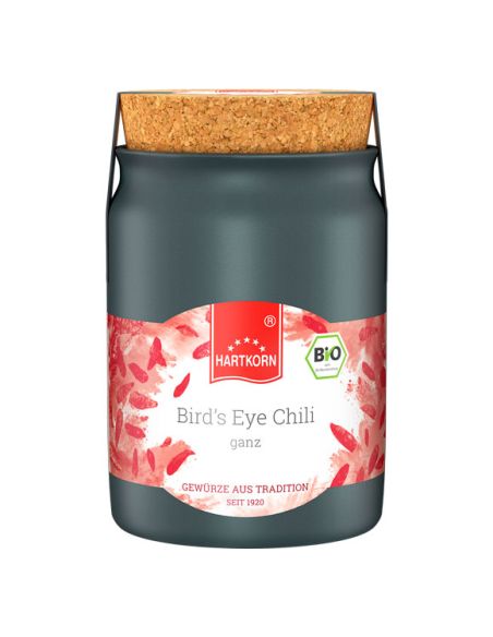 Schwarzes Keramiktöpfchen mit Korkdeckel, Etikett mit rotem Chili-Design und der Aufschrift „Bird’s Eye Chili ganz“. Schwarzes Keramiktöpfchen mit Korkdeckel, Etikett mit rotem Chili-Design und der Aufschrift „Bird’s Eye Chili ganz“.