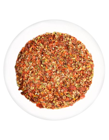 Weiße Schale mit grob geschroteten, rot-gelben Chili und Knoblauch.