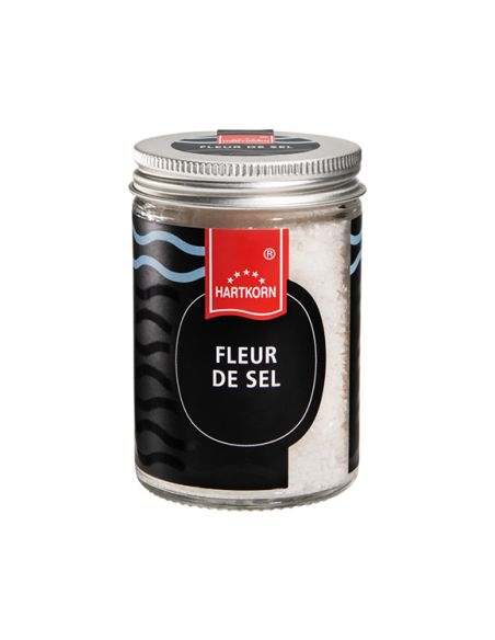 Glas mit silbernem Schraubdeckel. Etikett: „Fleur de Sel“ mit schwarzem Hintergrund und einem rot Abgebildeten Hartkorn Logo