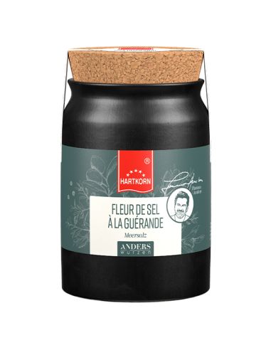 Keramiktopf in Schwarz mit breitem Korkdeckel und grauem Etikett. Die Aufschrift lautet  „Fleur de Sel À LA GUÉRANDE".