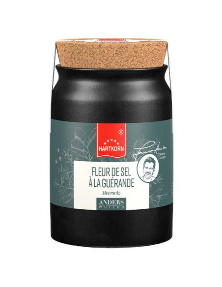Keramiktopf in Schwarz mit breitem Korkdeckel und grauem Etikett. Die Aufschrift lautet  „Fleur de Sel À LA GUÉRANDE".