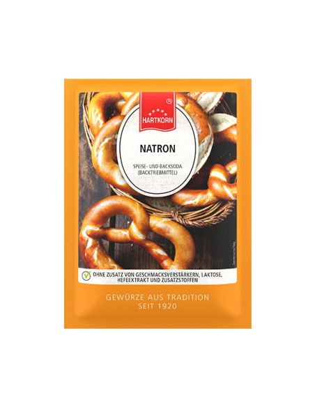 Flachbeutel mit der Aufschrift „Natron“ vor einem Glas mit Zitronenwasser und Beeren. Flachbeutel mit der Aufschrift „Natron“ vor einem Glas mit Zitronenwasser und Beeren.
