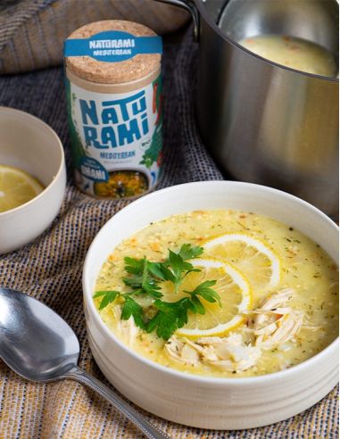 Cremige Hühnersuppe mit Zitrone, Petersilie und Gewürzbehälter im Hintergrund.