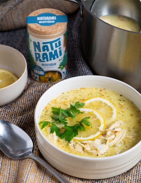 Cremige Hühnersuppe mit Zitrone, Petersilie und Gewürzbehälter im Hintergrund.